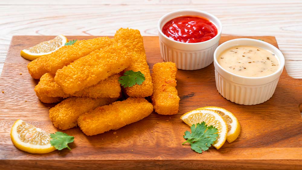 Fischstäbchen auf Holzbrett mit Saucen