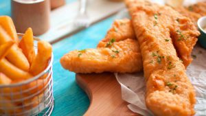 Backfisch auf Holzbrett mit Pommes