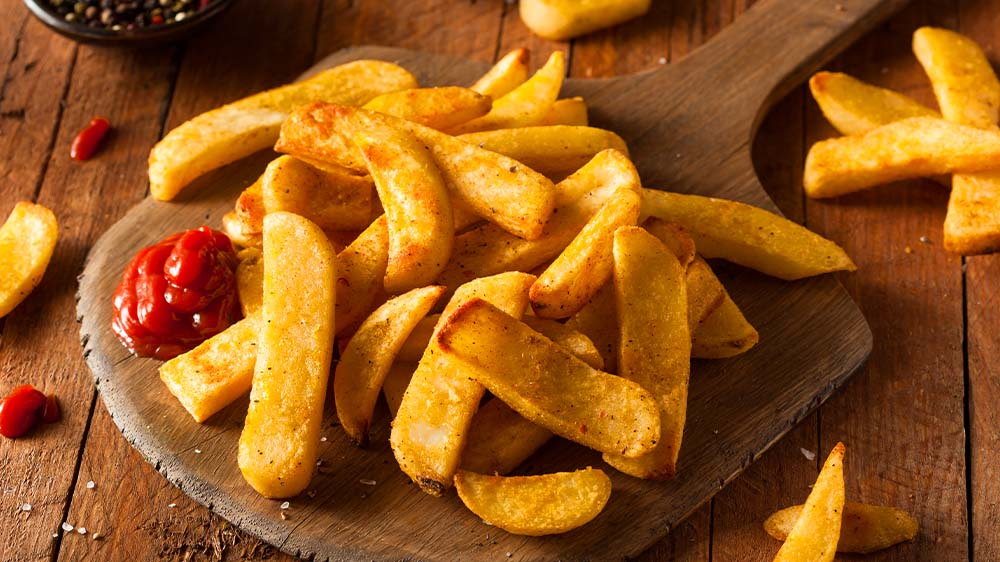 Pommes auf Holzbrett mit Gewürzen und Ketchup