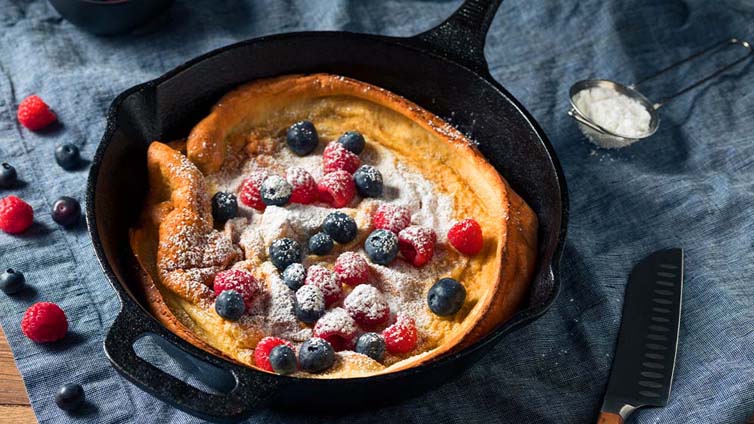 Dutch Baby mit Beeren und Puderzucker in Pfanne