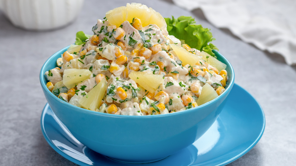 Eine Schüssel Geflügelsalat mit Ananas steht auf einem Teller.