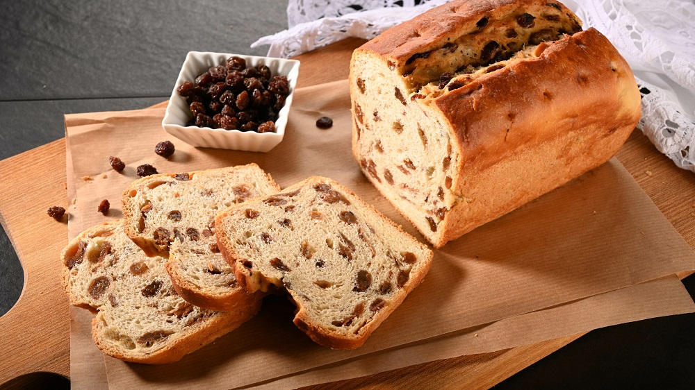 Rosinenbrot mit Rosinen auf einem Brett liegend.