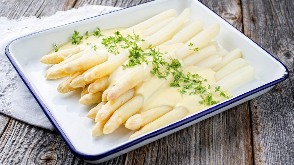 Weißer Spargel mit Sauce Hollandaise auf einem Teller.