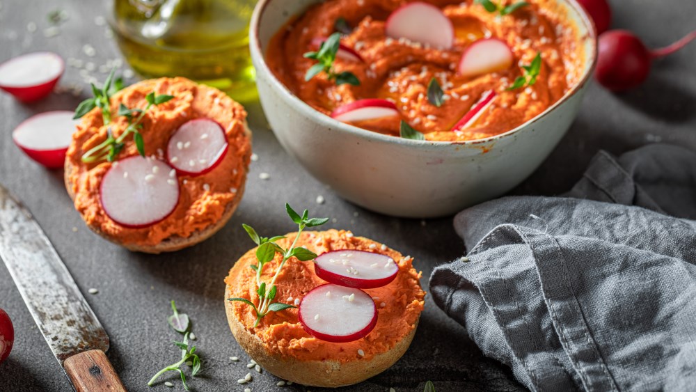 Tomatenbutter in einer Schale und auf einem Brötchen.